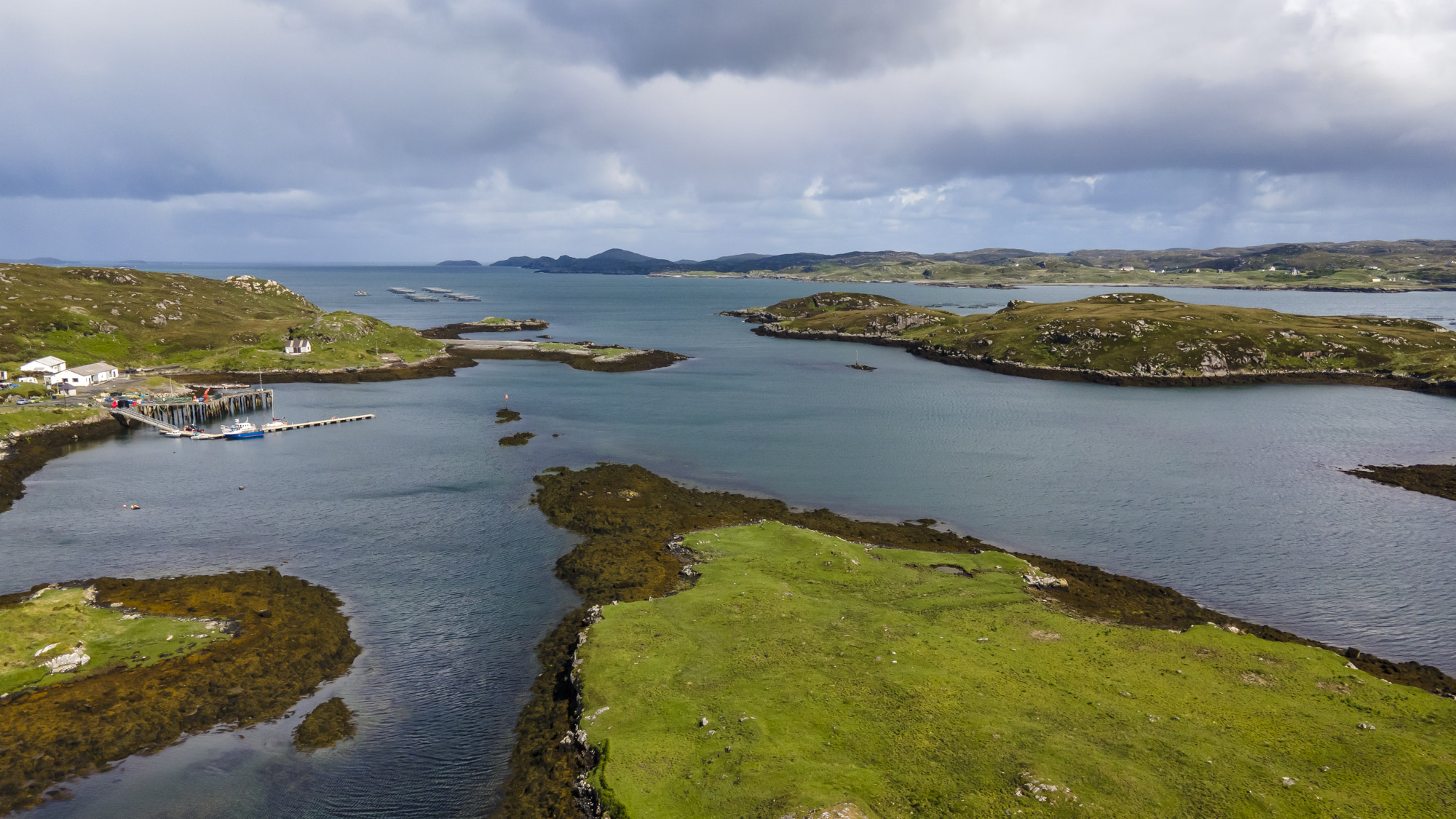 An aerial photo of a secure harbour with low green islands topped by rugged rocks surrounding it