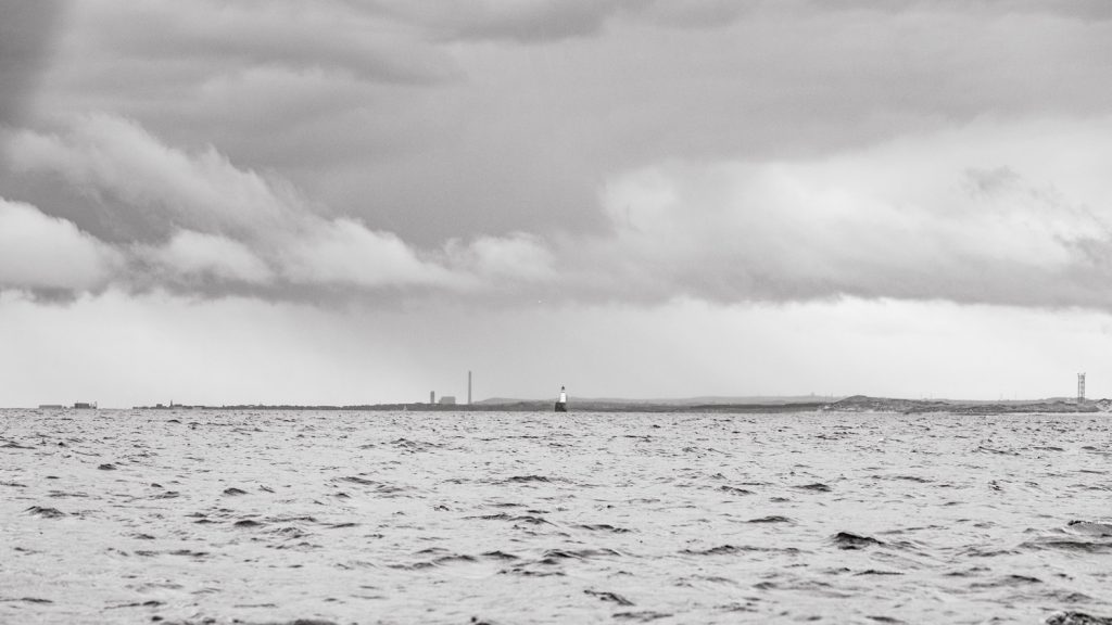 A low line of land slides along the horizon under a thickly clouded sky