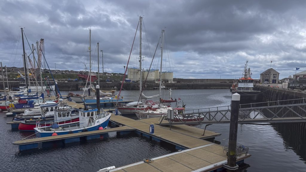 A crowded marina with yachts lying inside a basin under textured sky